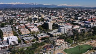An aerial image shows snow capped mountains on the horizon behind a view of apartment buildings and housing in the Westlake/MacArthur Park neighborhood March 2, 2023 in Los Angeles.