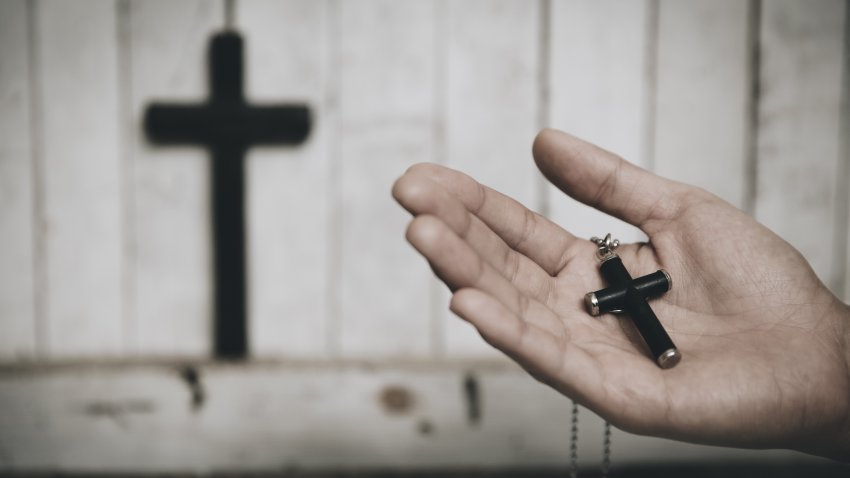 Woman hands holding wooden cross praying in the church,  spirituality and religion.  vintage tone.