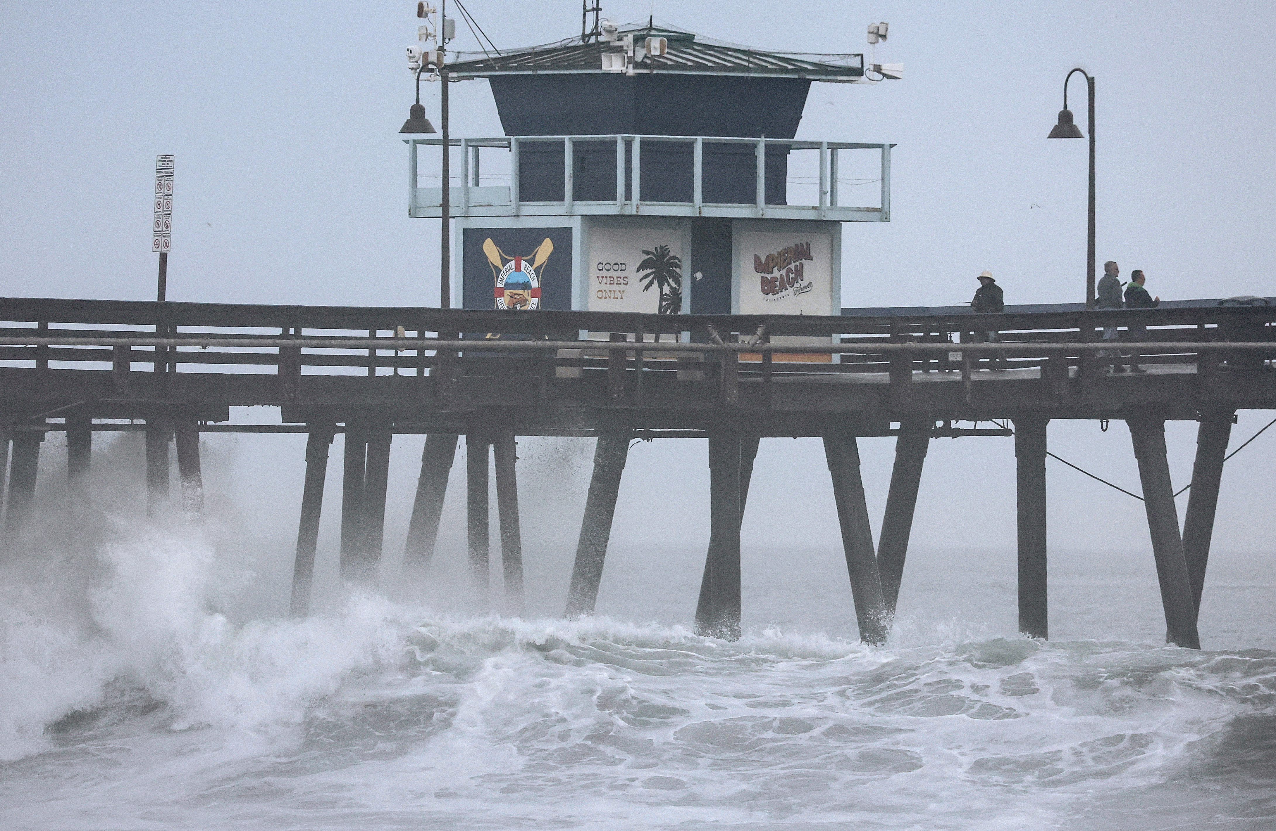 La gente se para en un muelle sobre el Océano Pacífico con la tormenta tropical Hilary acercándose al condado de San Diego el 20 de agosto de 2023 en Imperial Beach, California.