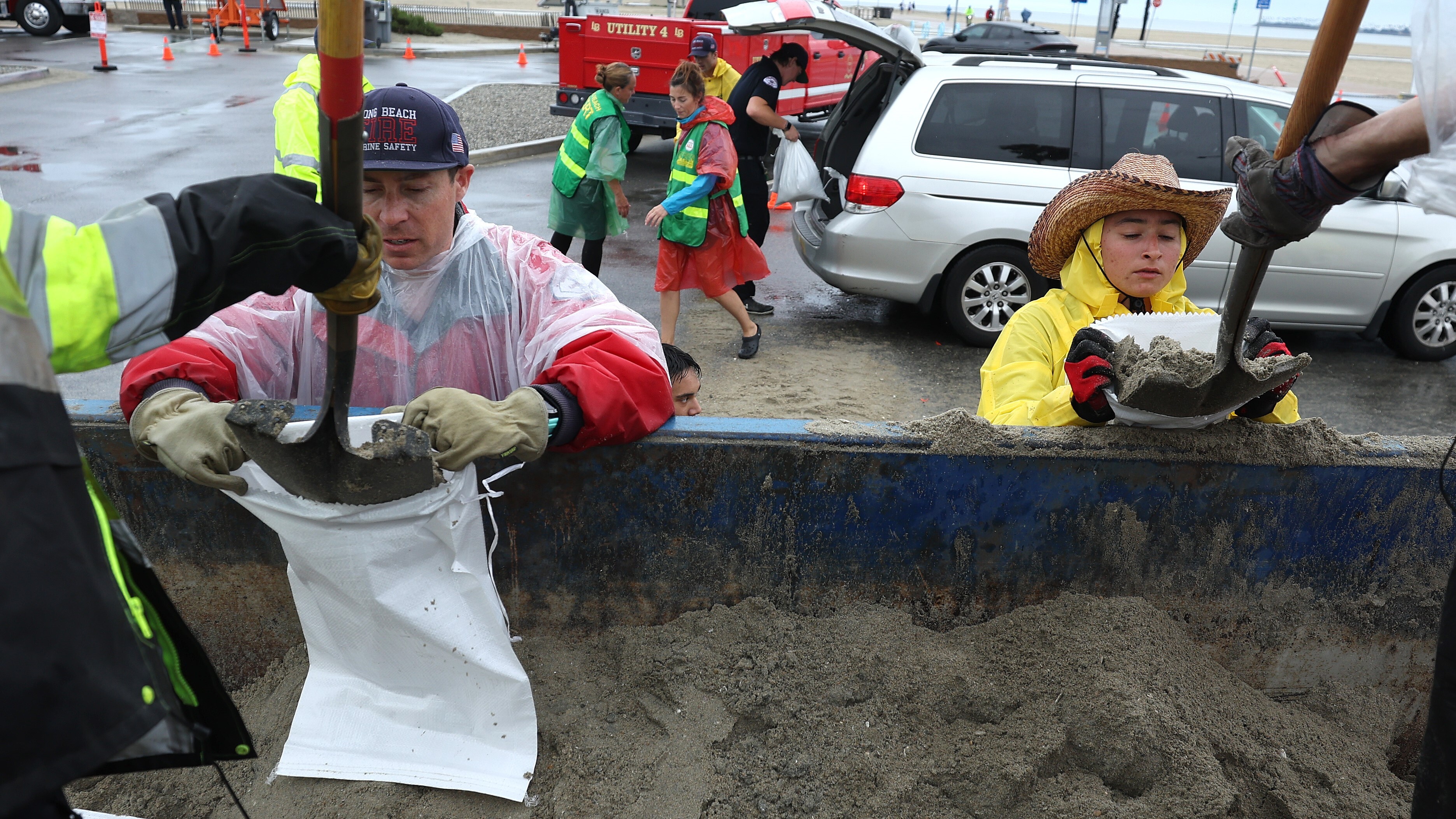 Voluntarios y miembros del Departamento de Bomberos de Long Beach llenan sacos de arena en Belmont Shore Beach el 20 de agosto de 2023.