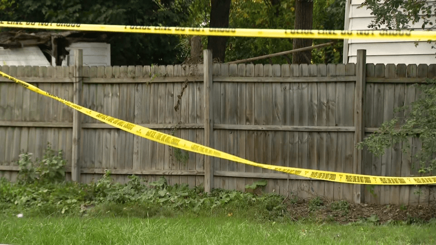 Police tape hangs along wooden fence