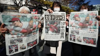 People pose with a special newspaper edition newspaper announcing that Japanese baseball star Shohei Ohtani has agreed to a contract with the Los Angeles Dodgers, on a street in Tokyo after the country woke up to the news of his contract signing, on Dec. 10, 2023.