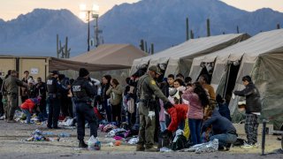 Agentes de Aduanas y Protección Fronteriza de EEUU instruyen a los inmigrantes sobre cómo separar artículos personales importantes de los que se desecharán en un centro de procesamiento de campo cerca de la frontera entre Estados Unidos y México el 8 de diciembre de 2023 en Lukeville, Arizona.