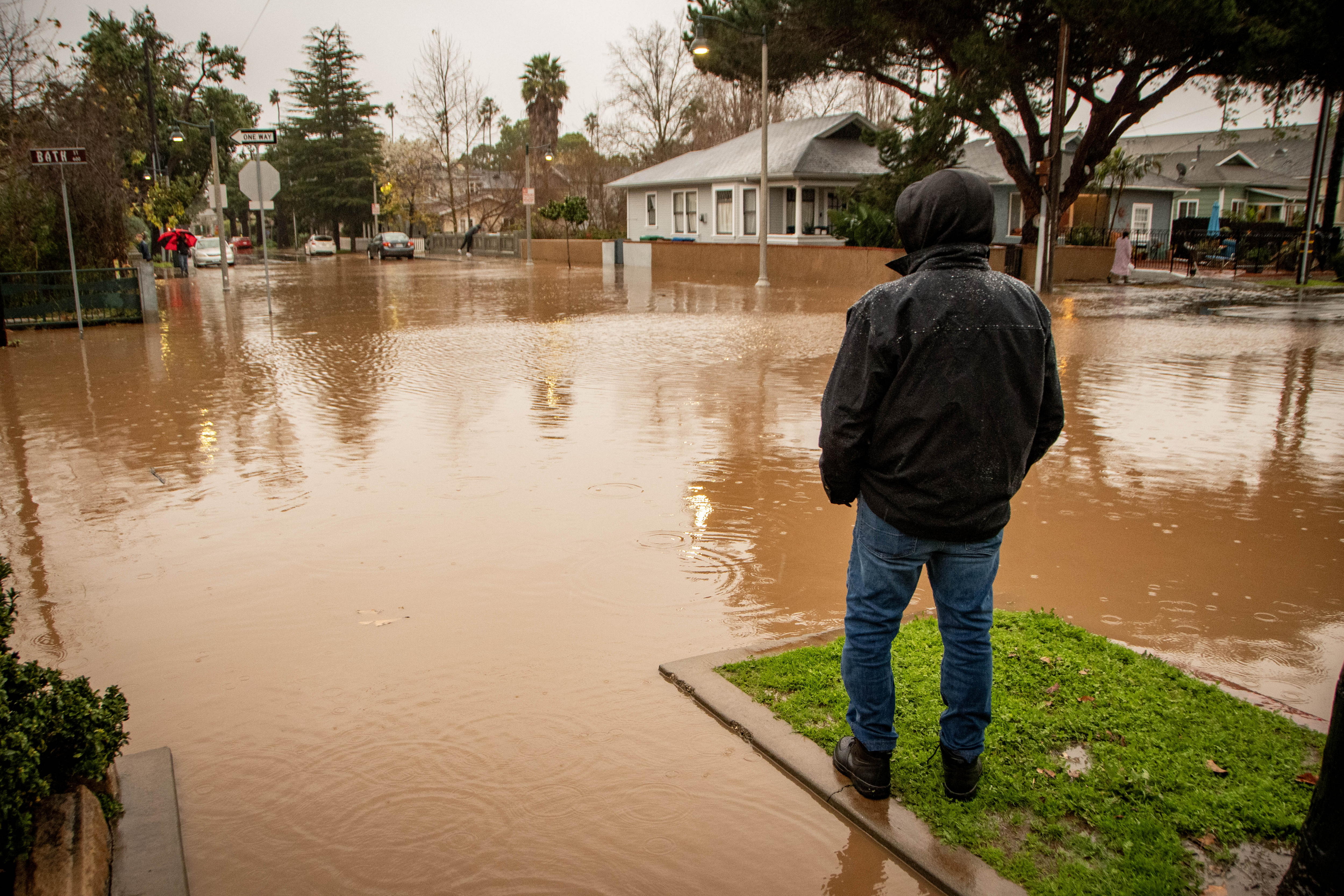 Un hombre fue registrado este domingo, 4 de febrero, al observar una intersección de calles inundadas, por efecto de las fuertes lluvias, en Santa Barbara (California, EE.UU.). EFE EFE/Erick Madrid