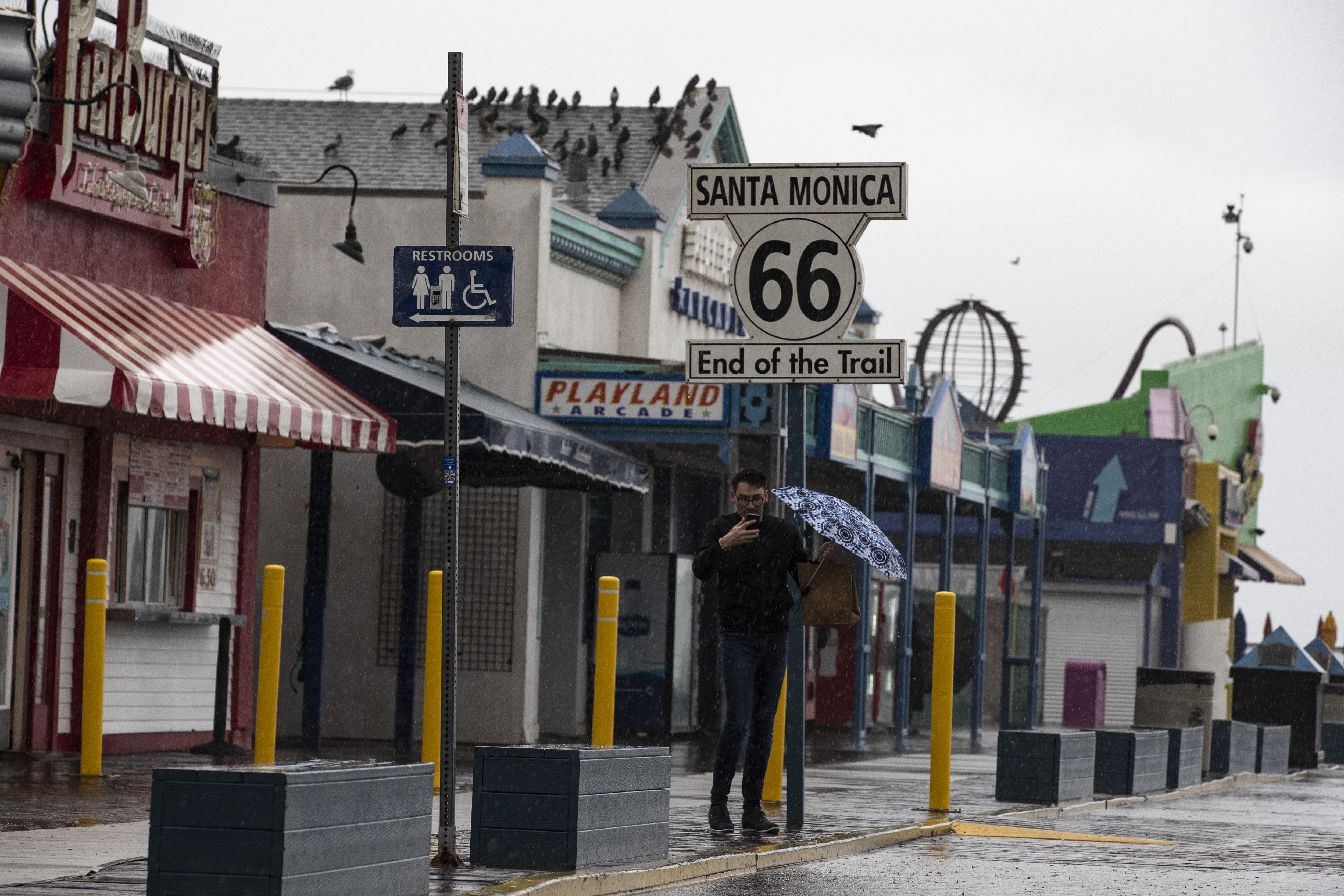 Un turista se toma un selfie en el muelle de Santa Mónica sosteniendo un paraguas mientras una tormenta azota el sur de California trayendo lluvias torrenciales y fuertes vientos, en Santa Mónica, California, este 5 de febrero de 2024.EFE/EPA/Etienne Laurent