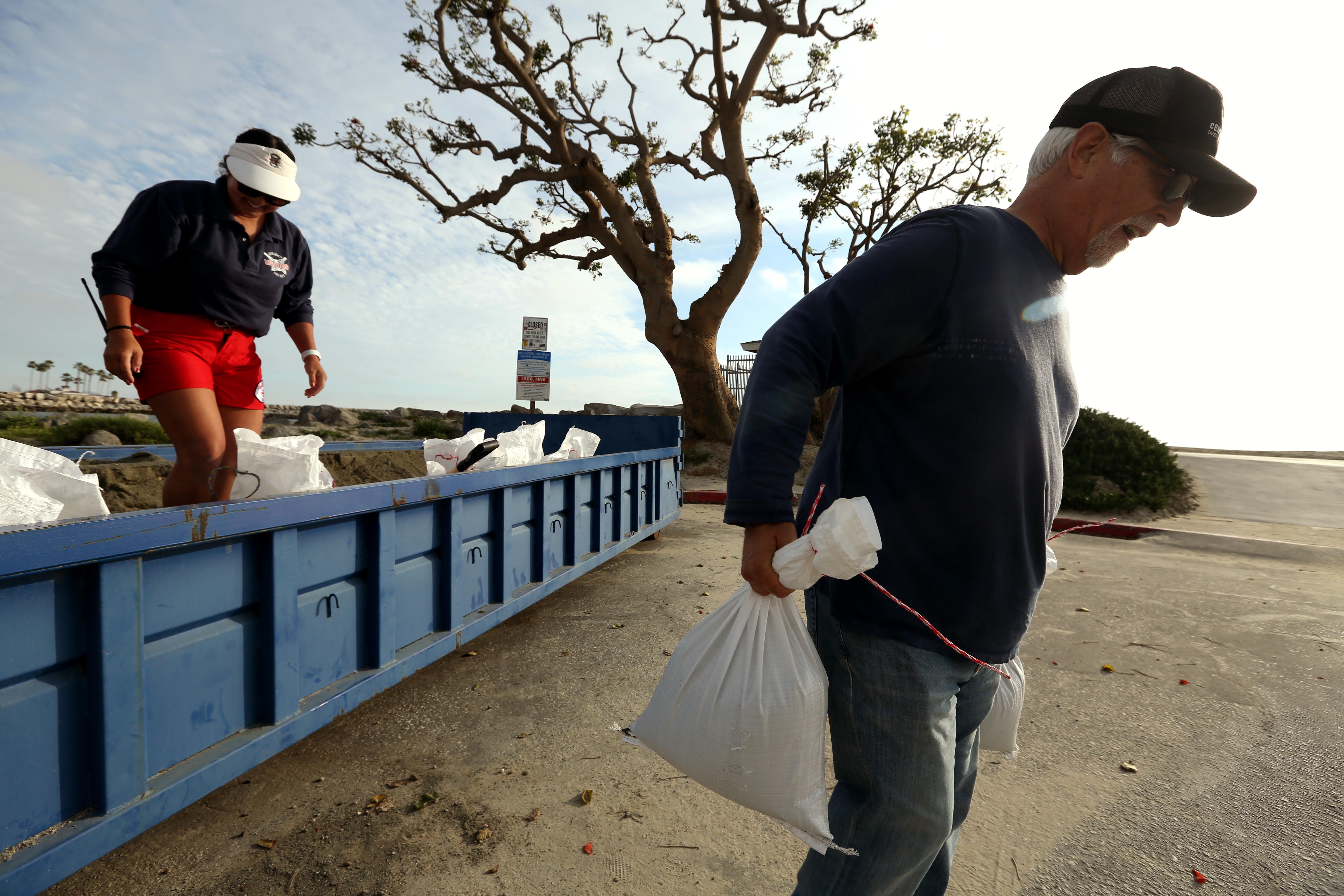 LONG BEACH, CA – 31 DE ENERO DE 2024 – – Don Kallenberg, de 68 años, residente de Belmont Shore, lleva bolsas de arena para prepararse para cualquier posible inundación de la próxima tormenta en la estación de salvavidas 72nd Place en Long Beach el 31 de enero de 2024. Salvavidas de Long Beach Molica Anderson, de 37 años, izquierda, llenó sacos de arena para los residentes. (Genaro Molina/Los Angeles Times vía Getty Images)