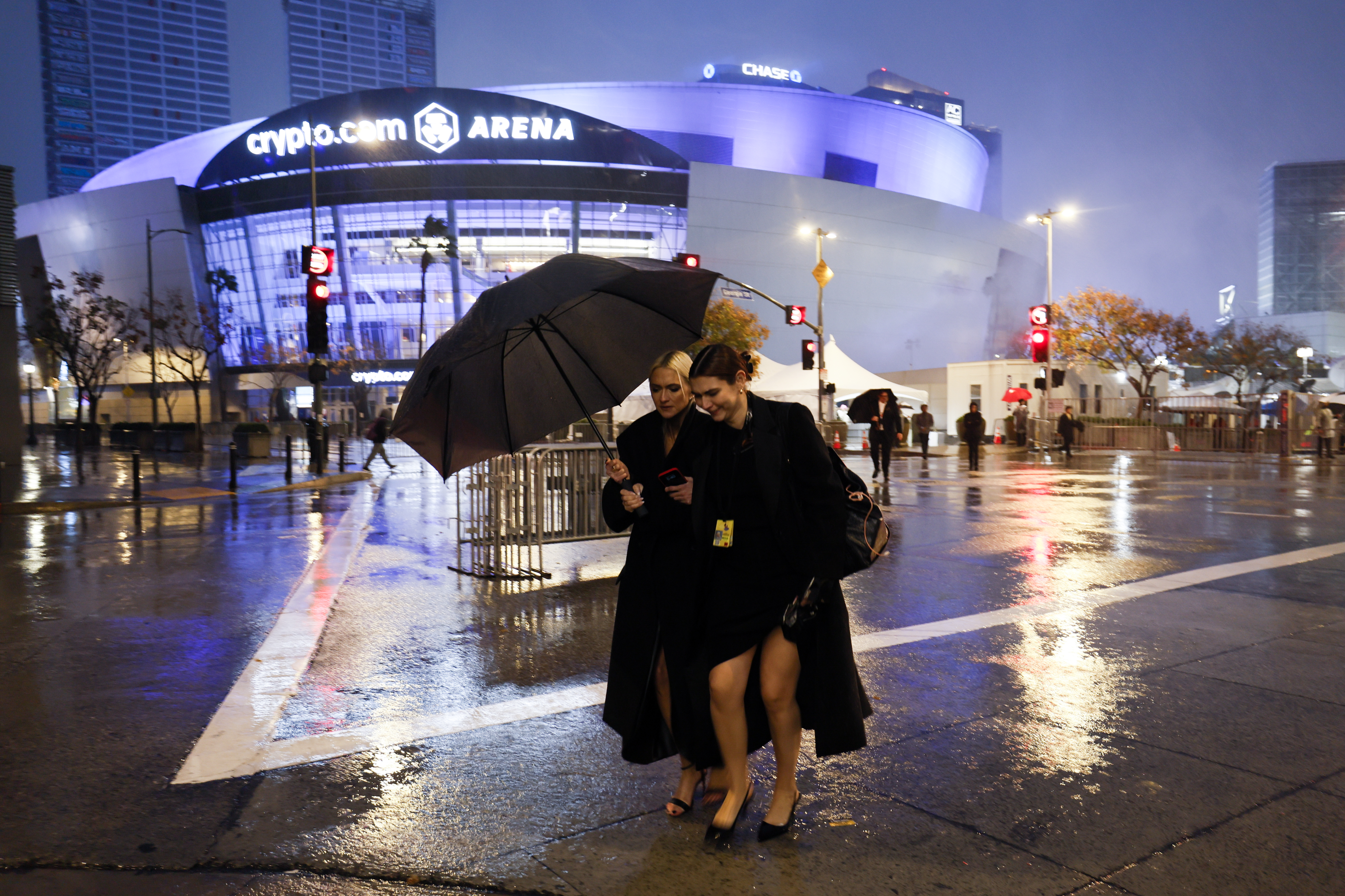 Los asistentes a la ceremonia de los Grammy corren entre la alfombra roja y un estacionamiento mientras otra tormenta azota el L.A. Live en Los Ángeles el domingo 4 de febrero de 2024.