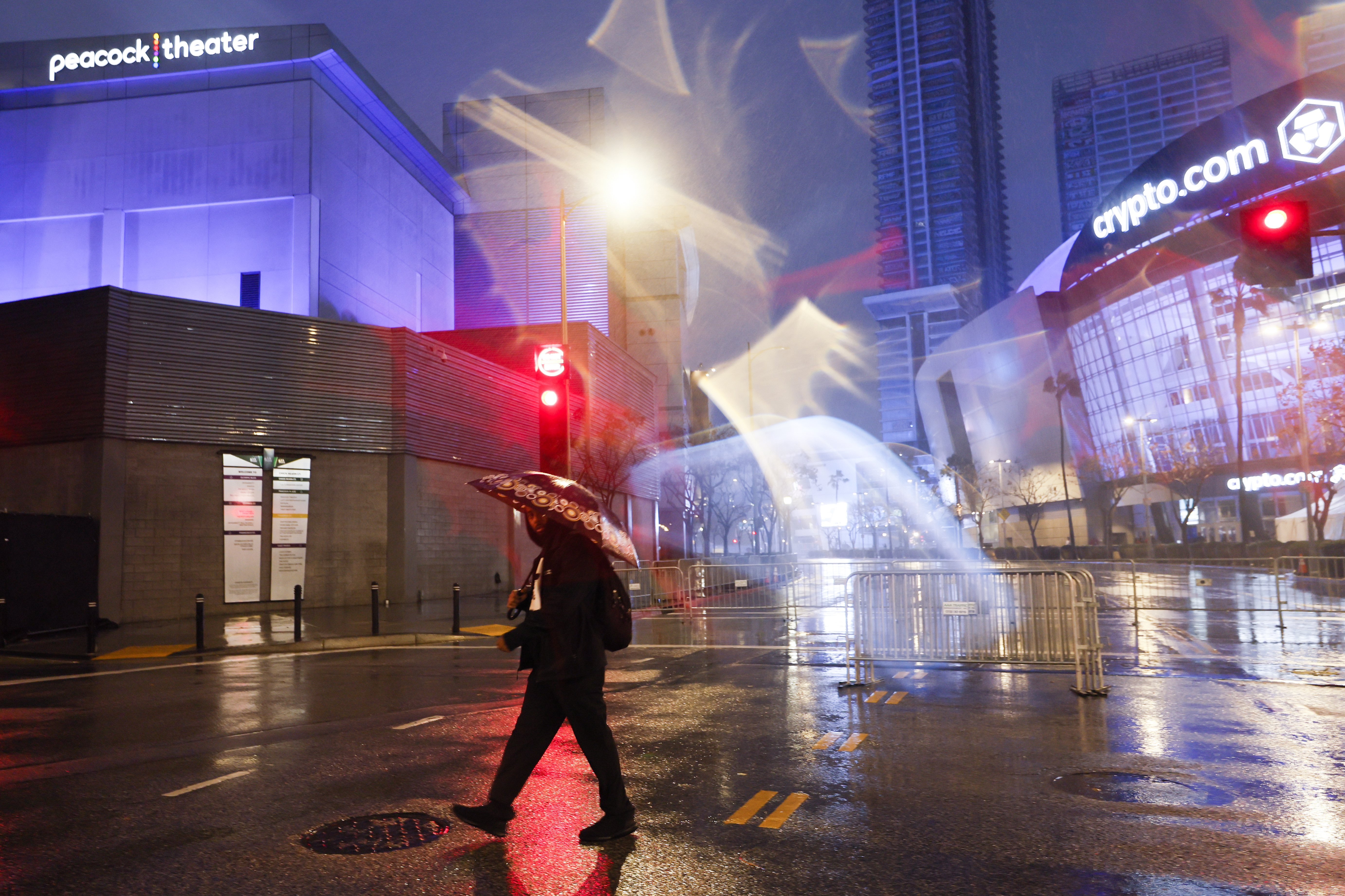 LOS ÁNGELES, CA – 4 DE FEBRERO: Las personas que asistieron a la ceremonia de los Grammy corren entre la alfombra roja y un estacionamiento mientras otra tormenta azota el L.A. Live en Los Ángeles el domingo 4 de febrero de 2024. (Allen J. Schaben / Los Angeles Times vía Imágenes falsas)