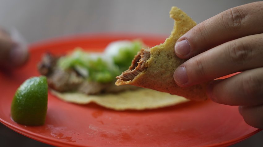 A customer holds his partially eaten taco at the Tacos El Califa de León taco stand, in Mexico City, Wednesday, May 15, 2024.