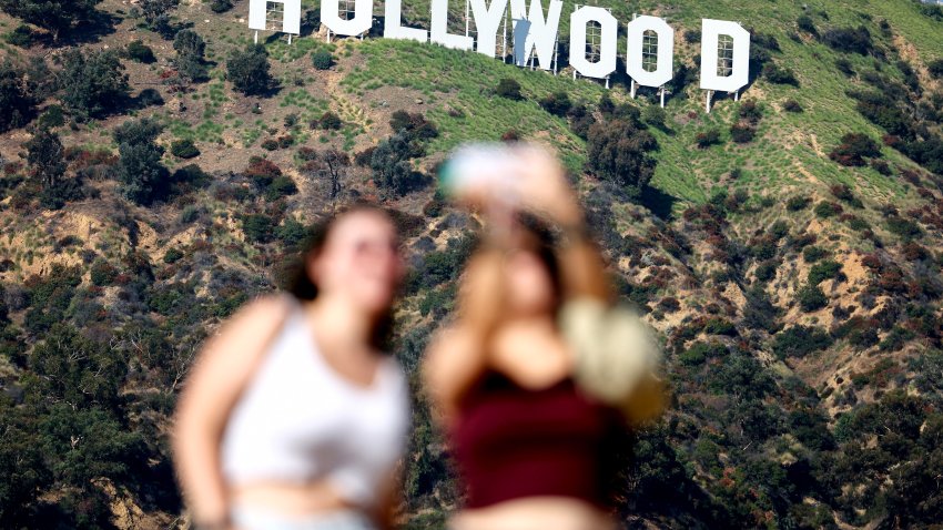 LOS ANGELES, CALIFORNIA – SEPTEMBER 25: People pose for photos beneath the Hollywood sign on September 25, 2023 in Los Angeles, California. Hollywood is awaiting the final vote on a tentative contract agreement between over 11,000 Writers Guild of America members and Hollywood studios in the nearly 150-day writers strike. (Photo by Mario Tama/Getty Images)