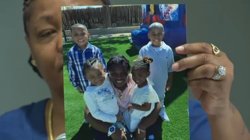 Melanie Gammage holds up a photo of her son Marquette Scott surrounded by his four children.