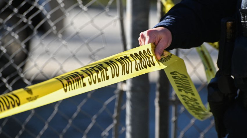 A police officer puts up police tape at a crime scene after a shooting