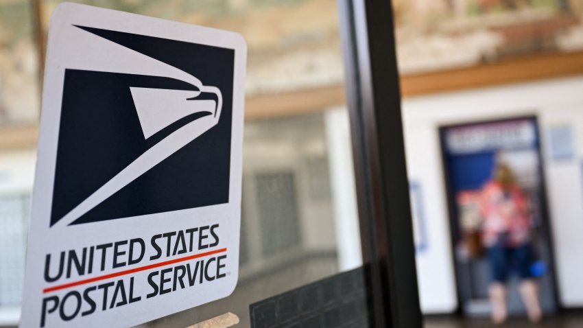 The United States Postal Service (USPS) logo is displayed on a door as a postal customer uses a self-service mail shipping kiosk to ship a package at a USPS post office on August 28, 2024 in Redondo Beach, California. (Photo by Patrick T. Fallon / AFP) (Photo by PATRICK T. FALLON/AFP via Getty Images)