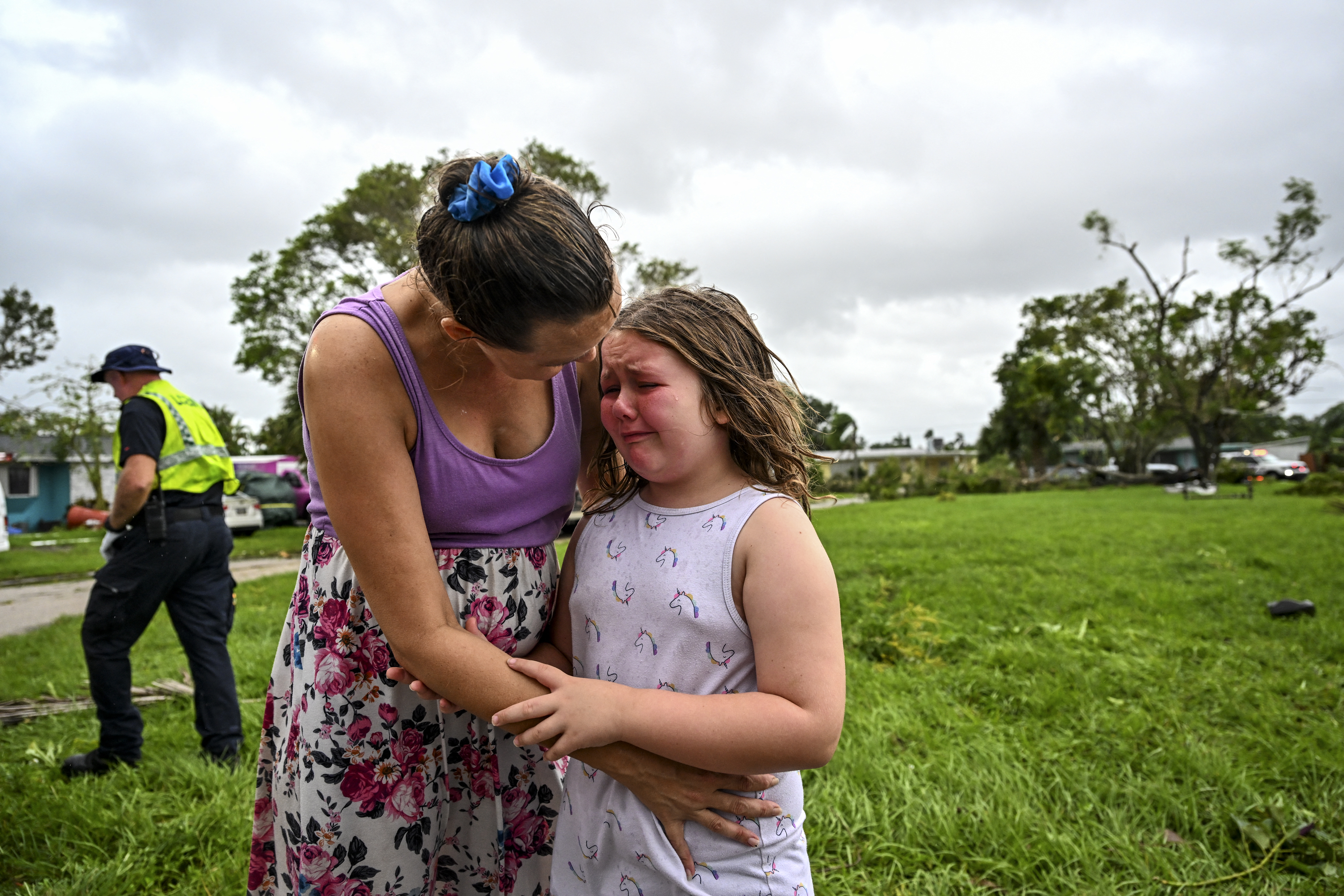 Samantha Dubberly consuela a su hija Alexa Haight mientras los médicos llevan a su abuelo a cuidados después de que resultó herido por un tornado que golpeó su casa en Fort Myers, Florida, el 9 de octubre de 2024.