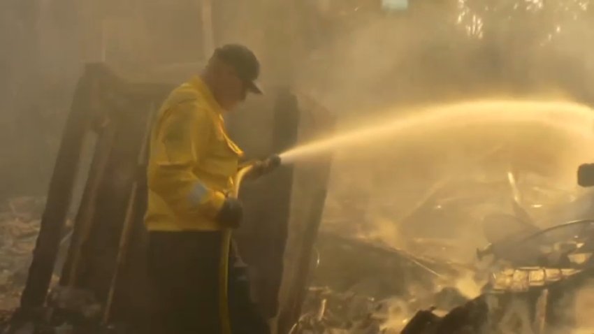 A firefighter douses flames while responding to the Franklin Fire in Malibu.