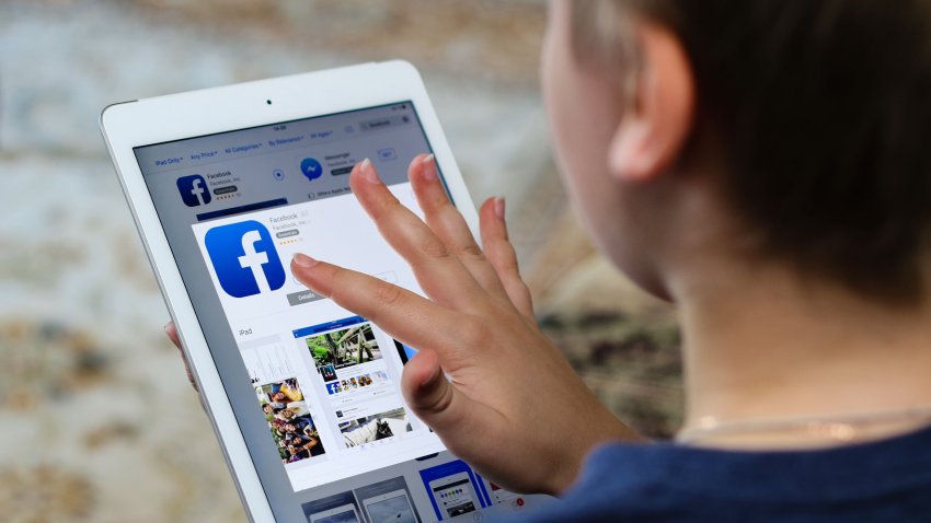 Minsk, Belarus – November 6, 2016: Boy teenager installs a program of the social network Facebook on iPad Air Apple from iTunes.