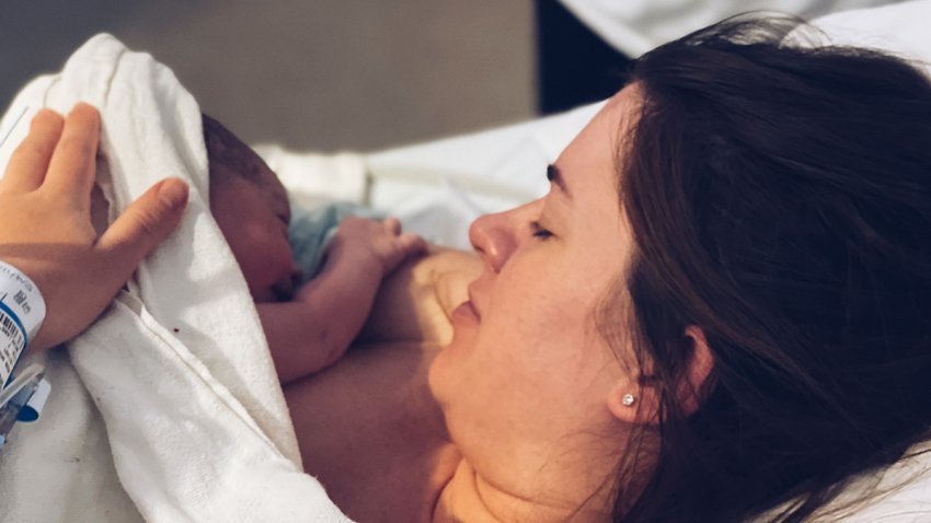 Mother looks at her newborn baby after childbirth. The first minutes after giving birth