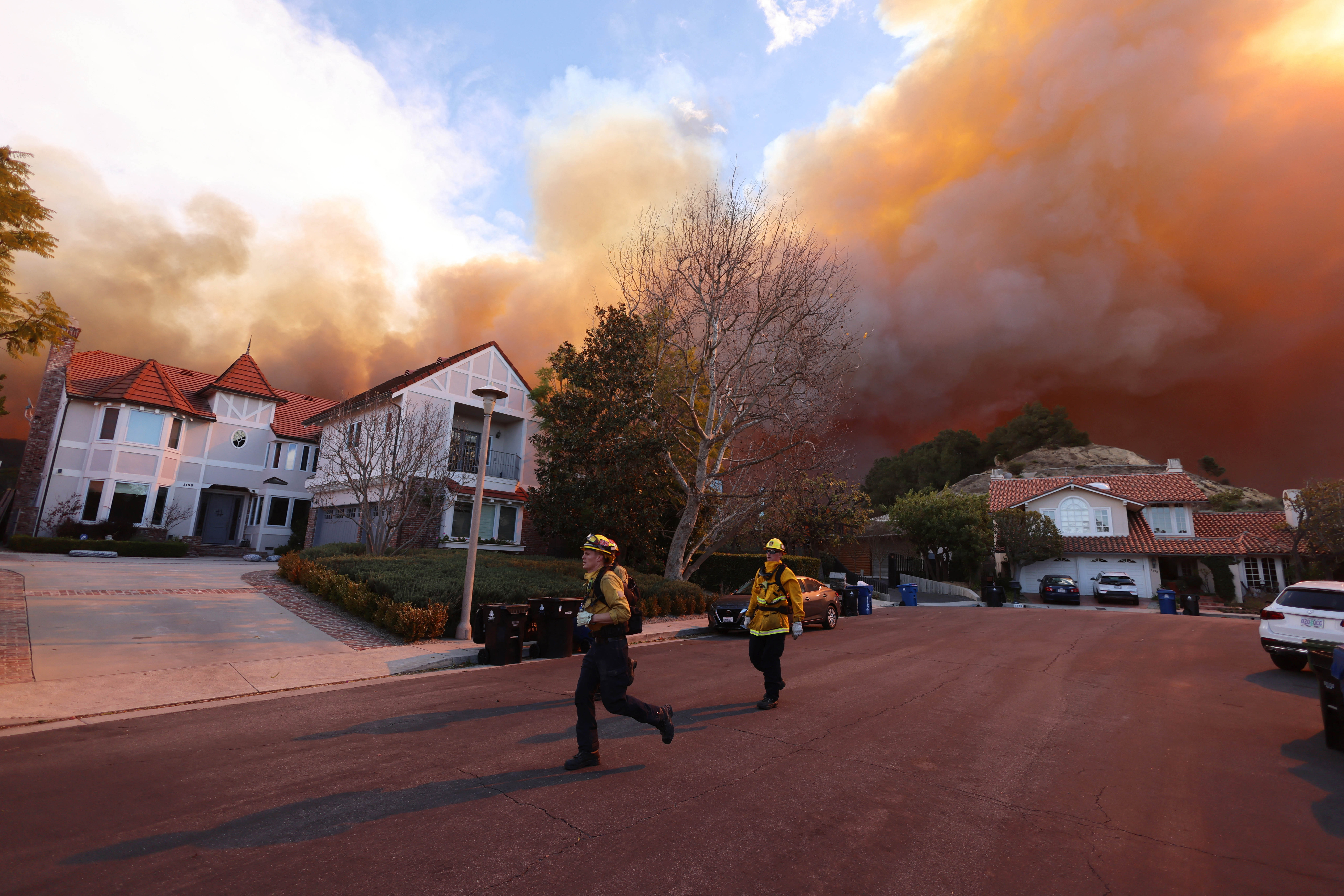 Los bomberos corren mientras un incendio forestal arde en Pacific Palisades, California, el 7 de enero de 2025. Un incendio forestal de rápido avance en un suburbio de Los Ángeles quemó edificios y provocó evacuaciones el martes mientras vientos "potencialmente mortales" azotaban la región. Más de 200 acres (80 hectáreas) estaban ardiendo en Pacific Palisades, un lugar exclusivo con casas de varios millones de dólares en las montañas de Santa Mónica, cerrando una carretera clave y cubriendo el área con un espeso humo. (Foto de David Swanson / AFP) (Foto de DAVID SWANSON/AFP vía Getty Images)