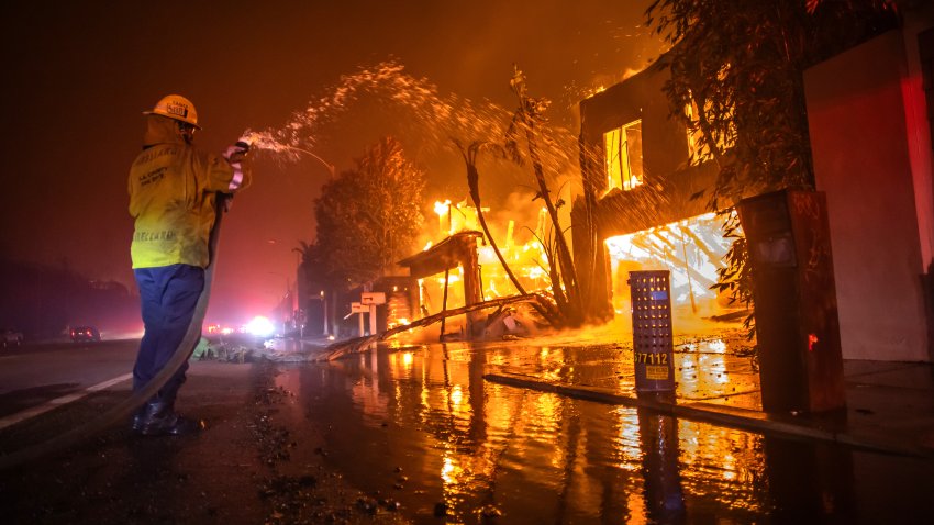 LOS ANGELES, CALIFORNIA – JANUARY 8: A firefighter battles the Palisades Fire while it burns homes at Pacific Coast Highway amid a powerful windstorm on January 8, 2025 in Los Angeles, California.  The fast-moving wildfire has grown to more than 2900-acres and is threatening homes in the coastal neighborhood amid intense Santa Ana Winds and dry conditions in Southern California. (Photo by Apu Gomes/Getty Images)