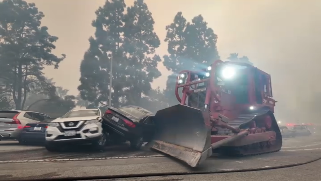 A fire department bulldozer moves abandoned cars in Pacific Palisades Tuesday Jan. 7, 2025.