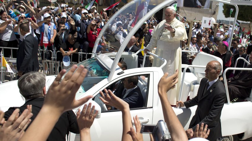 Pope Francis waves to the crowd, from his pope-mobile, as he leaves the Manger Square after presiding over an open-air mass on May 25, 2014, outside the Church of the Nativity in the West Bank Biblical town of Bethlehem. Pope Francis invited Israeli President Shimon Peres and his Palestinian counterpart Mahmud Abbas to his home in the Vatican for a “heartfelt prayer” for peace. AFP PHOTO/ AHMAD GHARABLI        (Photo credit should read AHMAD GHARABLI/AFP via Getty Images)
