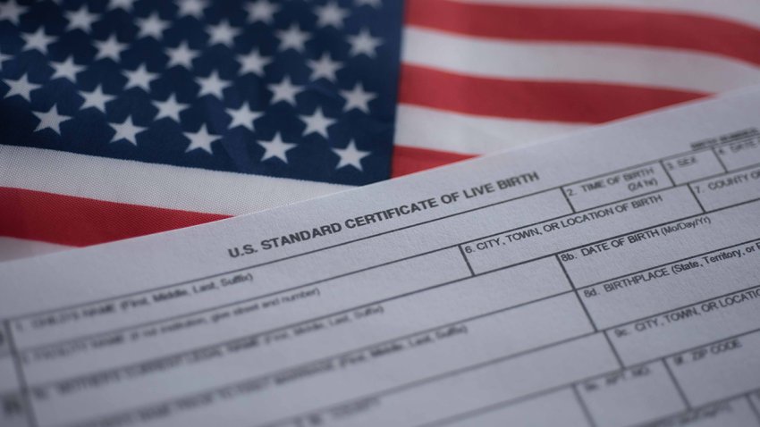 U.S. standard certificate of live birth application form next to flag of USA. Birthright citizenship concept.