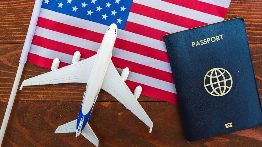 Flag of United States with port and toy airplane on wooden background. Flight travel concept