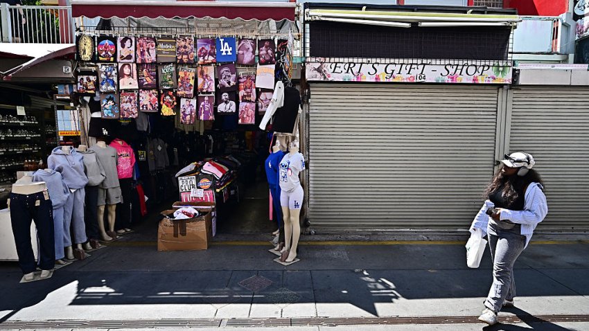 A woman walks past a closed business along Santee Alley in Downtown Los Angeles July 3, 2025. The usually vibrant neighborhood filled with boutiques and shops has become a ghost town amid raids by US Immigration and Customs Enforcement (ICE) agents carrying out President Donald Trump’s hard-line policy of sweeping up and deporting undocumented immigrants. (Photo by Frederic J. BROWN / AFP) (Photo by FREDERIC J. BROWN/AFP via Getty Images)