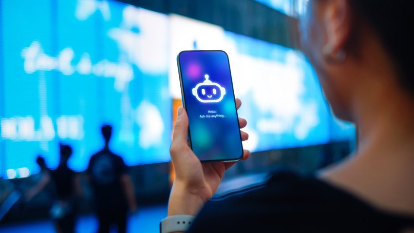 Asian woman standing against illuminated digital display on the street in city, speaking to virtual assistant, chatting AI chatbot app on smartphone. Concept of VR and AR technologies. Metaverse and futuristic data. People, AI, innovation and technology