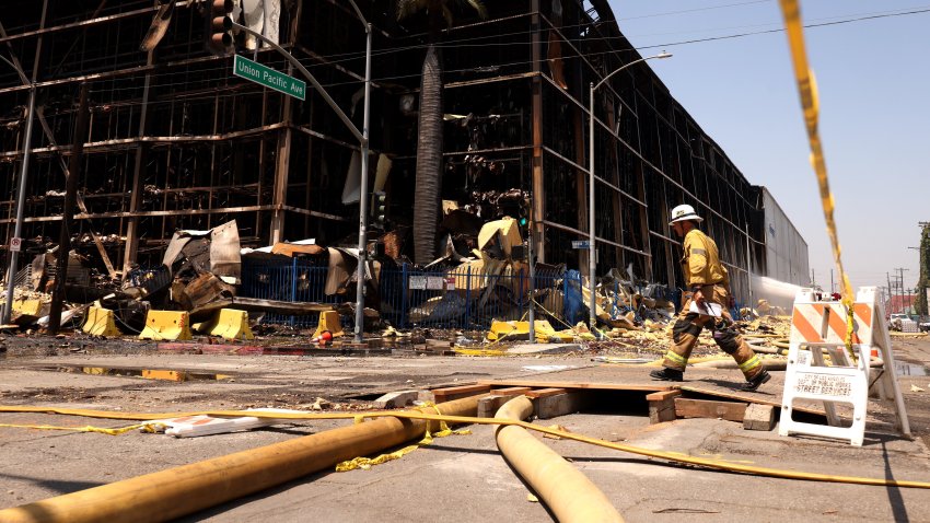 A firefighter walks by a fire ravaged section of the 500,000-square-foot Lineage cold storage warehouse along Indiana Street in the Boyle Heights on June 24, 2026.