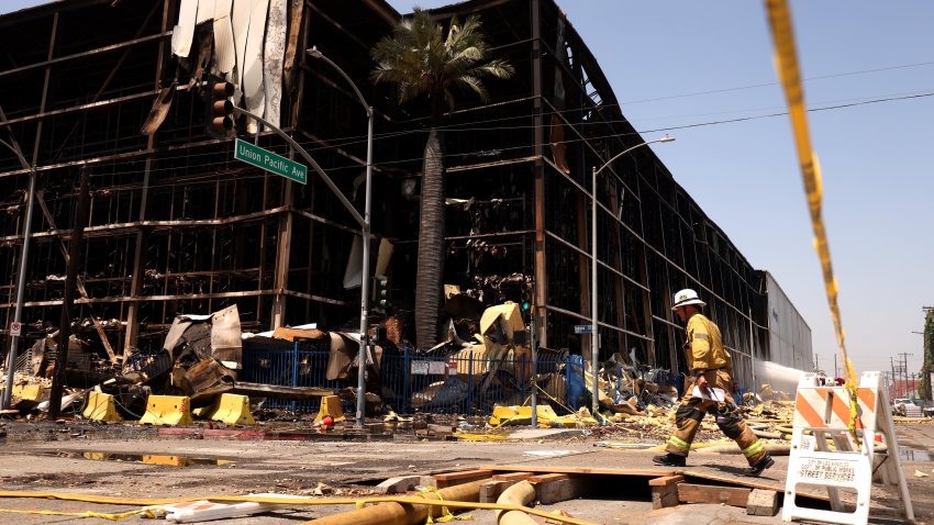 A firefighter walks by a fire ravaged section of the 500,000-square-foot Lineage cold storage warehouse along Indiana Street in the Boyle Heights on June 24, 2026.