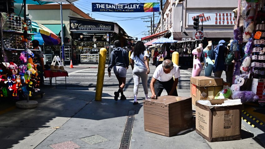 A shopkeeper opens boxes in front of a business along Santee Alley in the Fashion District of Downtown Los Angeles, July 3, 2025. The usually vibrant neighborhood filled with boutiques and shops has become a ghost town amid raids by US Immigration and Customs Enforcement (ICE) agents carrying out President Donald Trump’s hard-line policy of sweeping up and deporting undocumented immigrants. (Photo by Frederic J. BROWN / AFP) (Photo by FREDERIC J. BROWN/AFP via Getty Images)