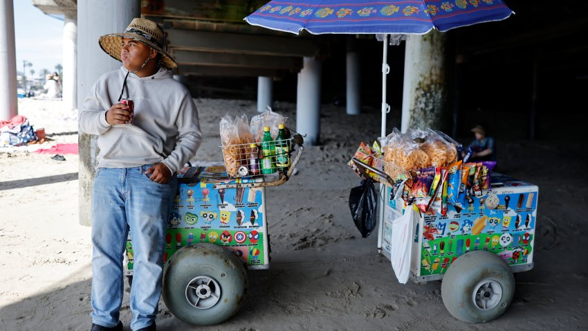 a beach vendor stays cool in the shade of the pier at Santa Monica State Beach amid a heat wave across Southern California on July 15, 2026 in Santa Monica.